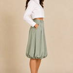Matching side view with lighter sage bubble-hem pants, a cropped white button-up, and mule heels